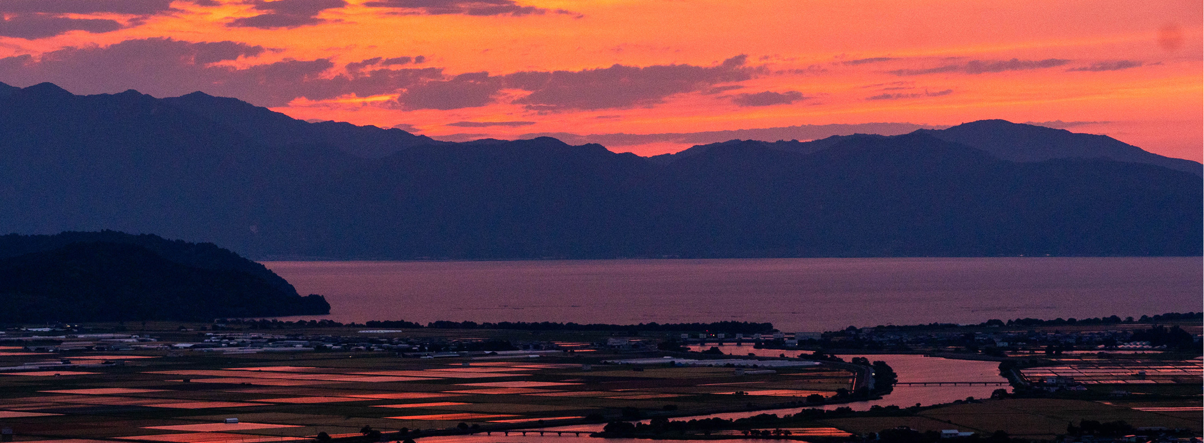 夕焼けに染まる琵琶湖と東近江市の田園